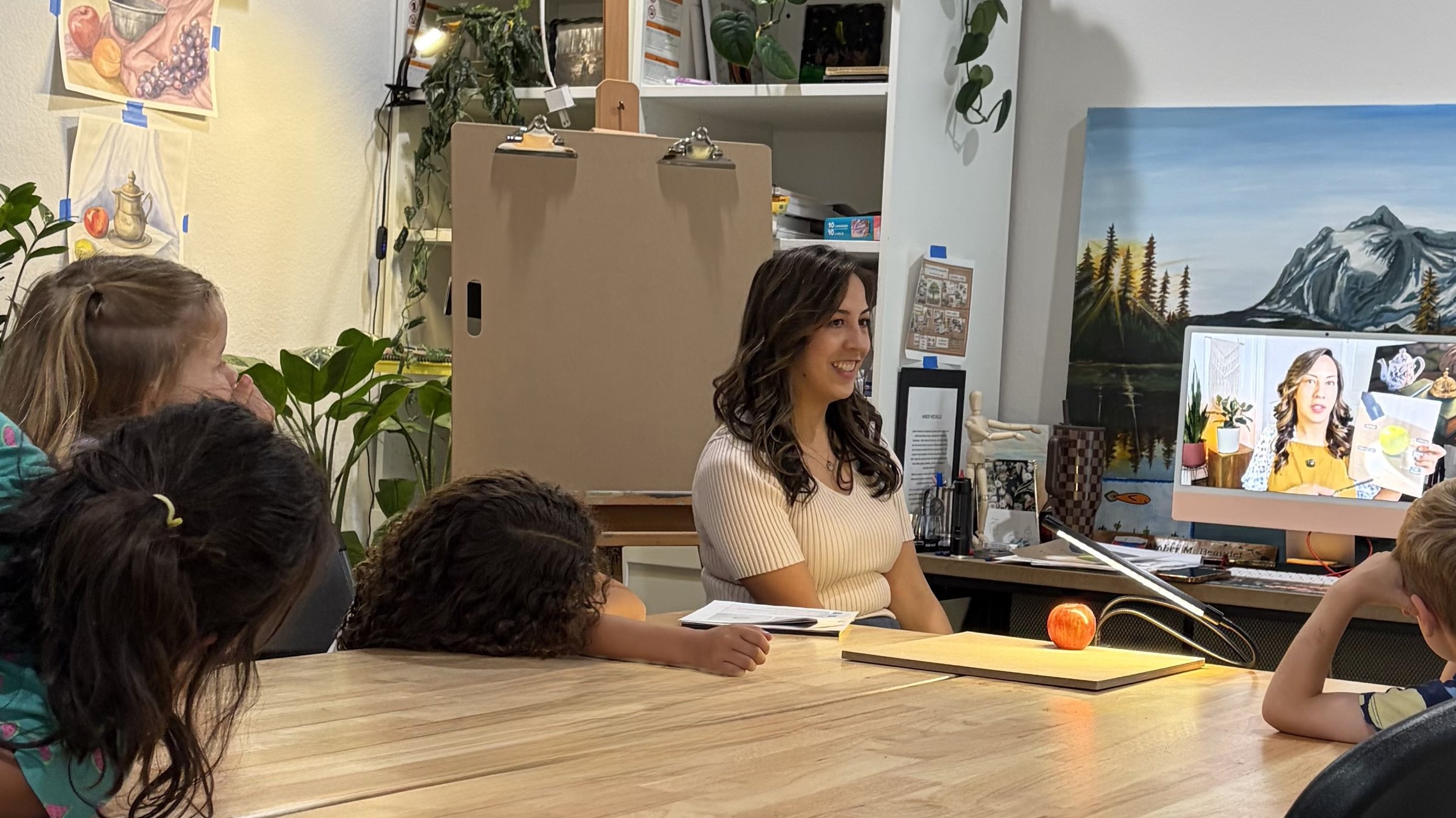 Amber Michelle teaching students in the studio, with the Created to Create curriculum displayed on screen