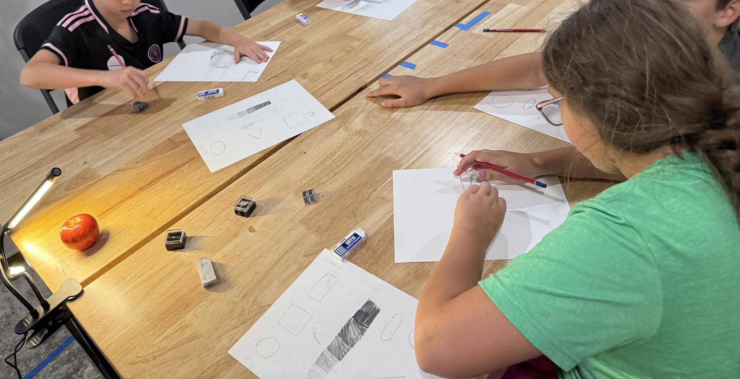 Students focused on executing their drawings at the studio table