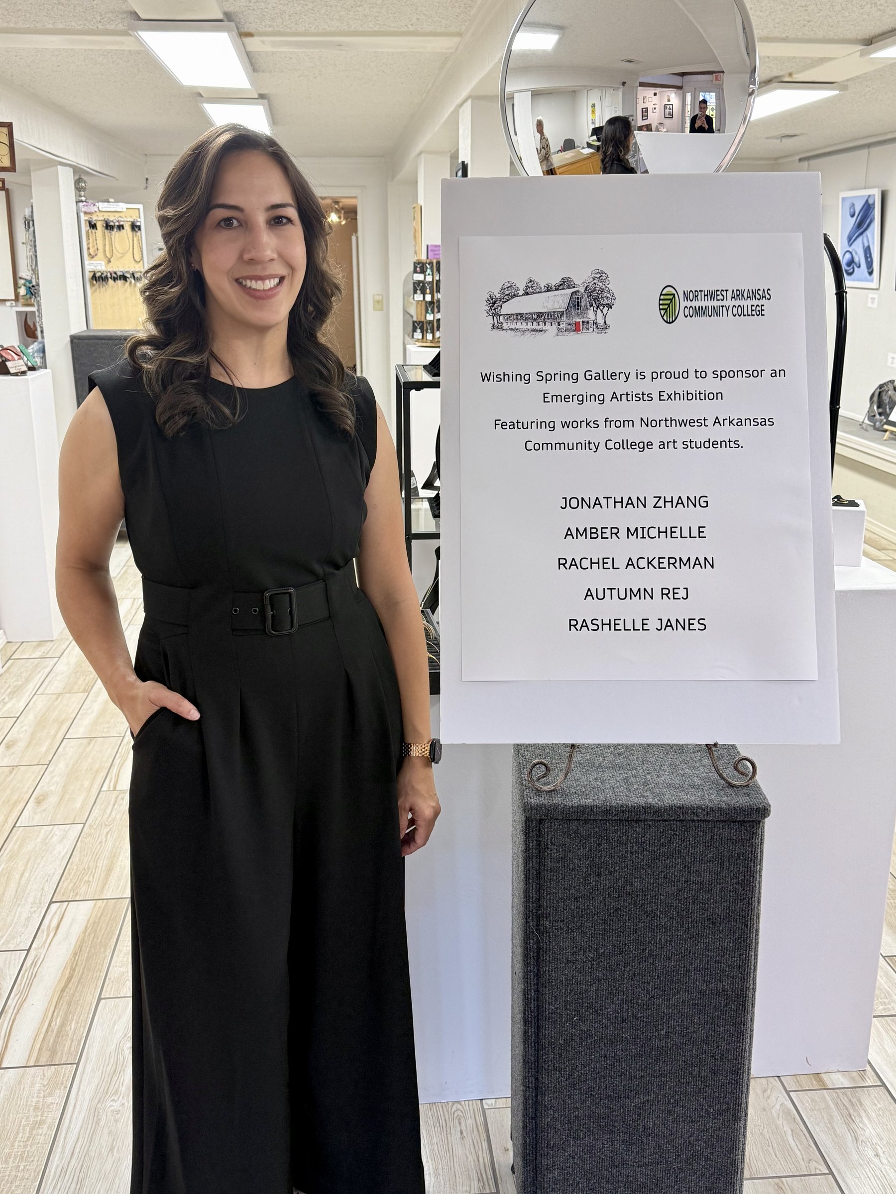 Amber Michelle beside the Emerging Artists Exhibition sign at Wishing Spring Gallery