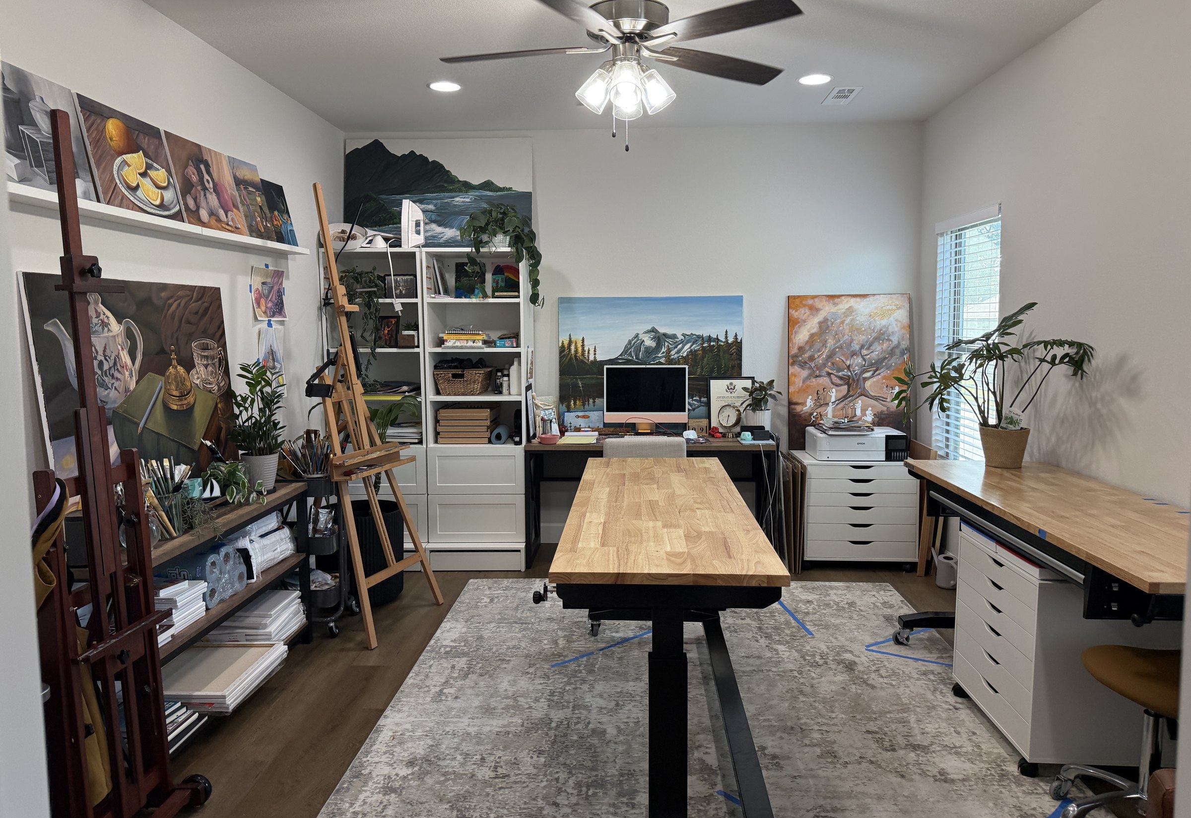 Amber Michelle's studio workspace, with easel, work table, and studio artwork